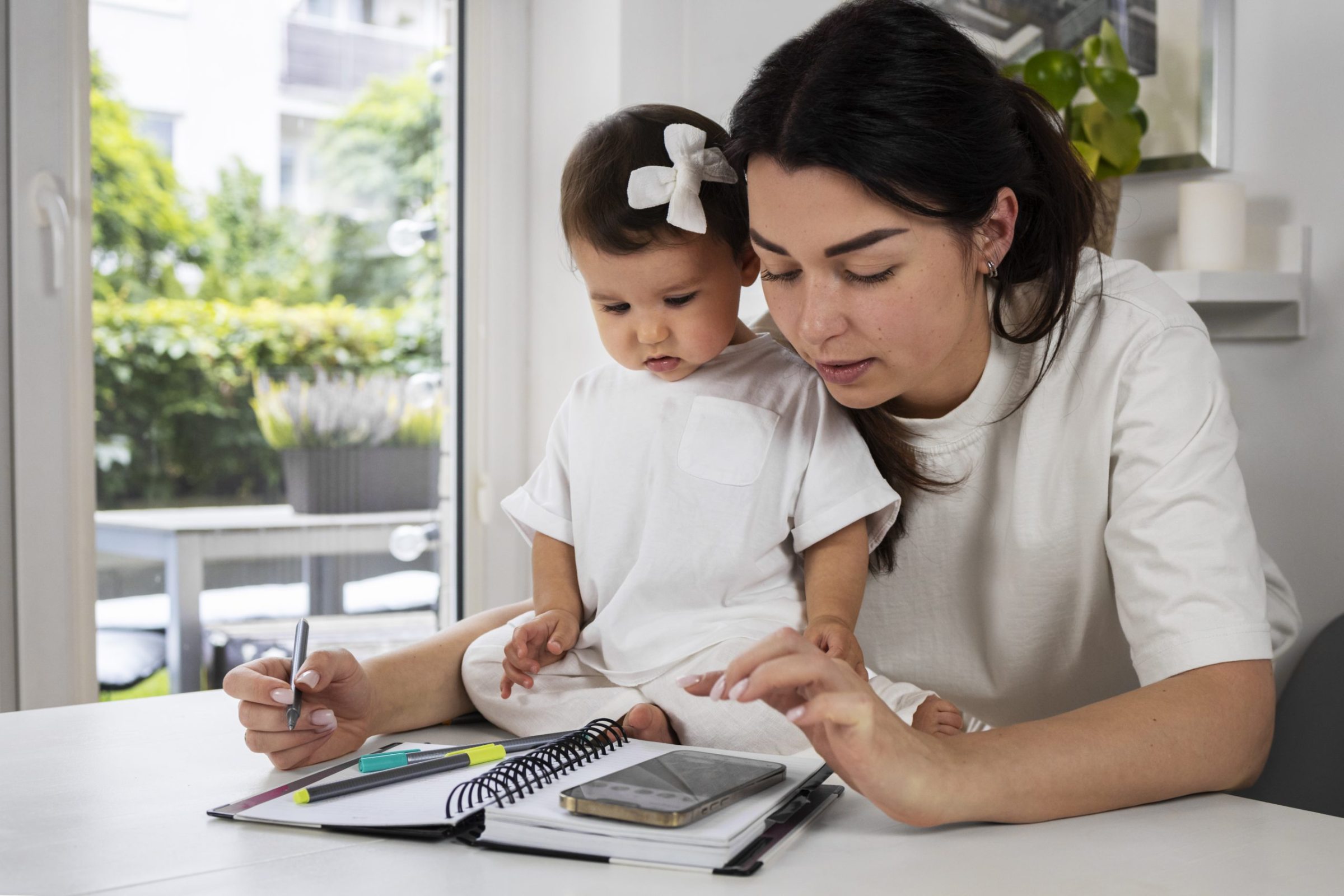 A woman and child engage at a table with a notebook, representing the collaborative efforts of child support lawyers.