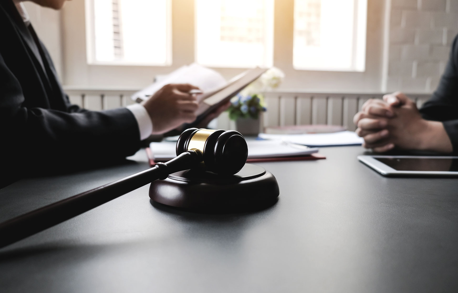 A lawyer and judge seated at a table, engaged in discussion with a tablet and pen, focused on litigation matters.