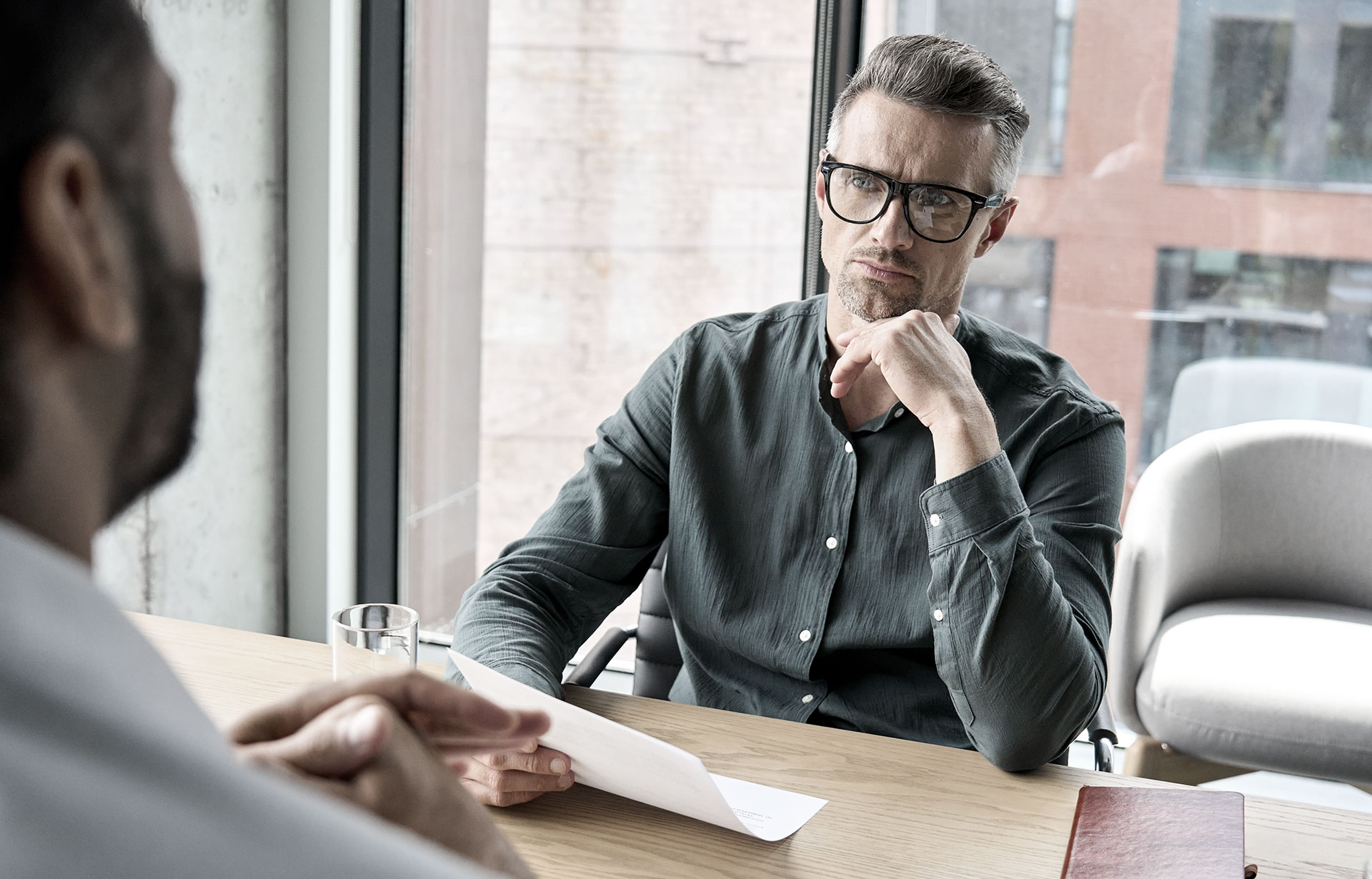 Two men, one wearing glasses, engage in conversation at a table, symbolizing employment law discussions in Perth.