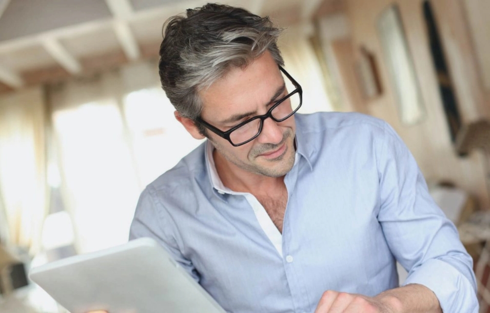 A man in glasses engages with a tablet computer, symbolizing the integration of technology in property law services in Perth.