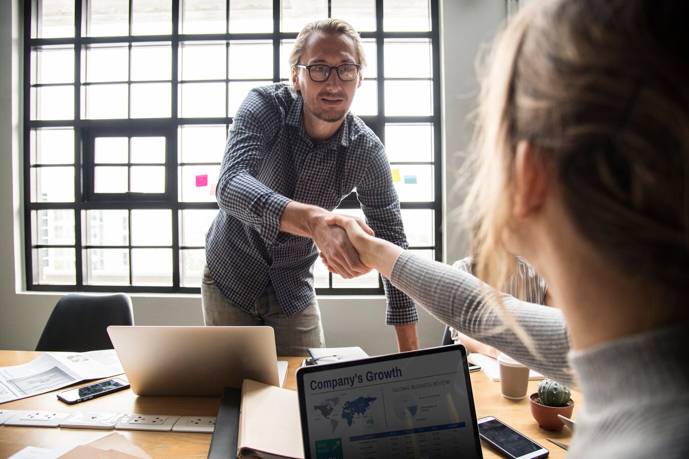 A handshake between a man and woman at a table, representing a partnership in commercial law in Perth.