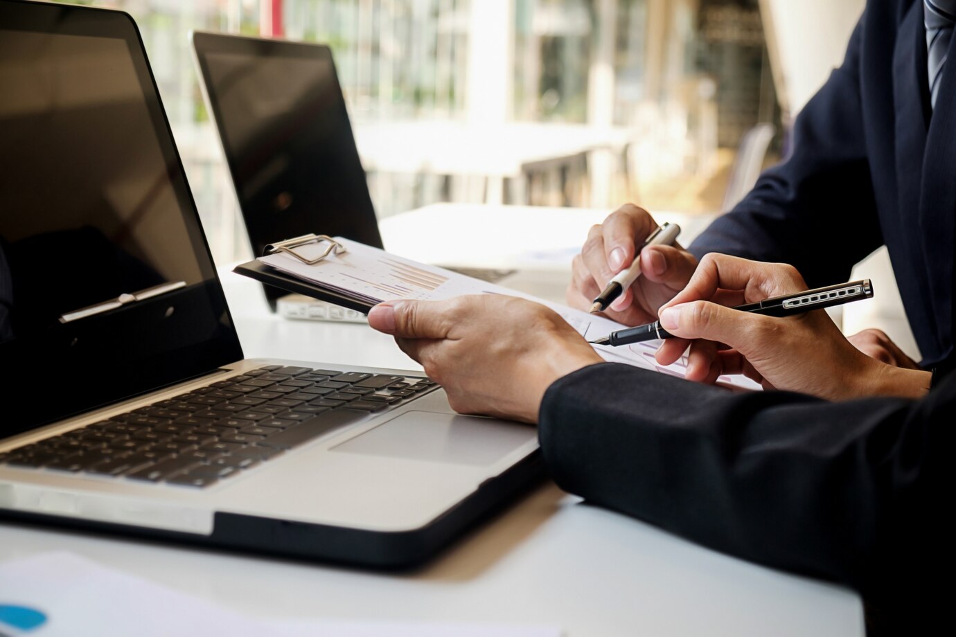 Two individuals in business suits engage with a laptop, symbolizing the work of commercial lawyers in Perth.