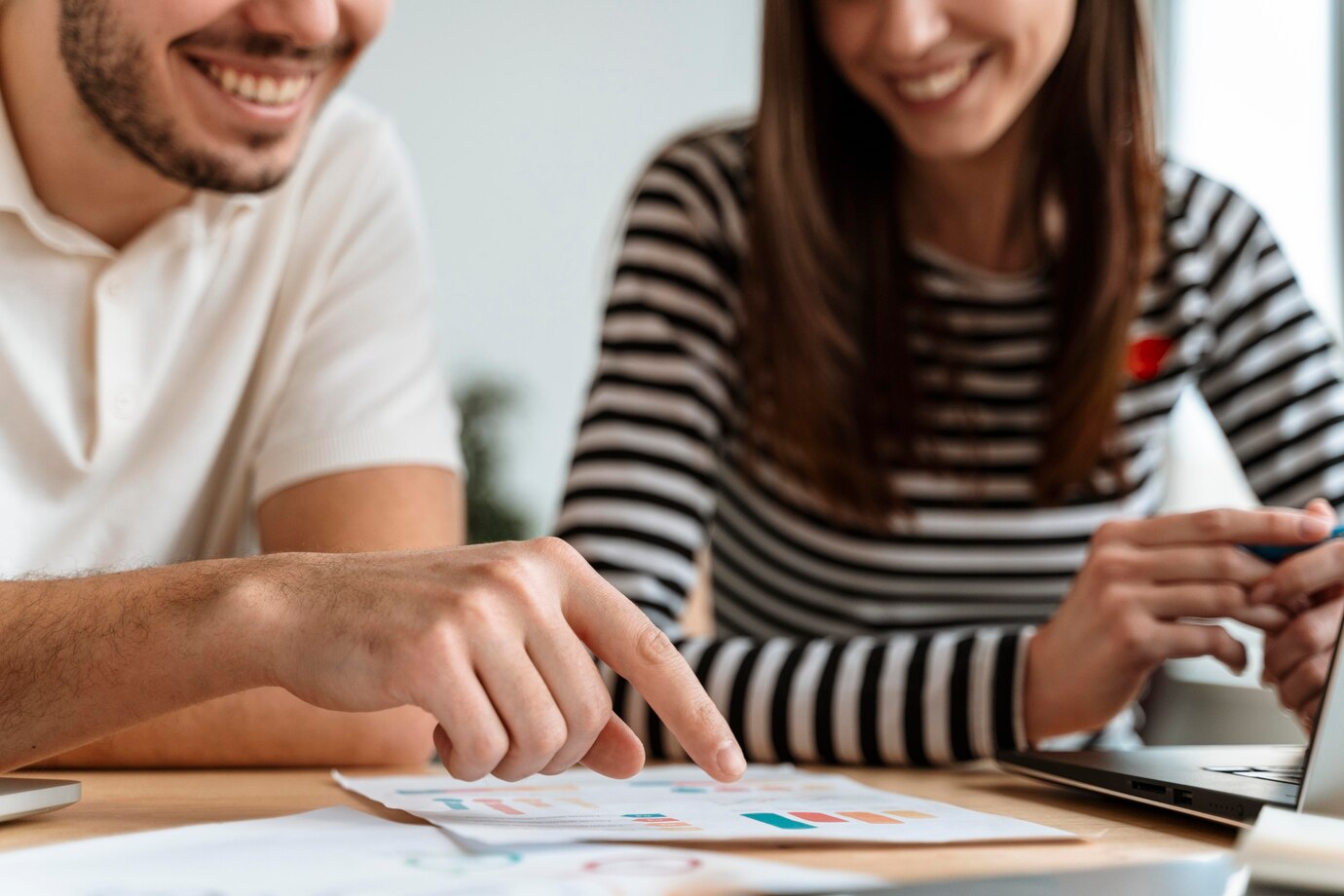 A man and woman analyze a laptop display, engaged in a discussion about finance and securities law in Perth.