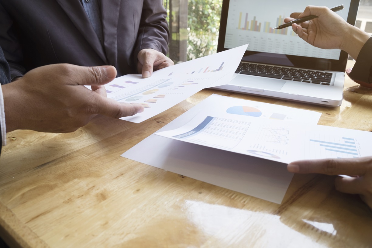 A group of business individuals analyzing graphs and discussing financial agreements in a professional environment in Perth.