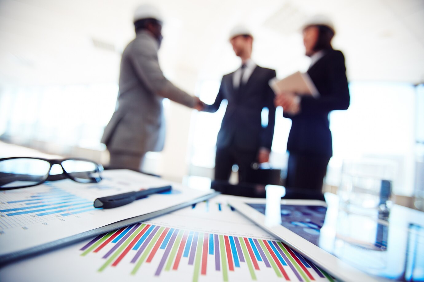 Business professionals shaking hands over documents and graphs, symbolizing collaboration in commercial law in Perth.
